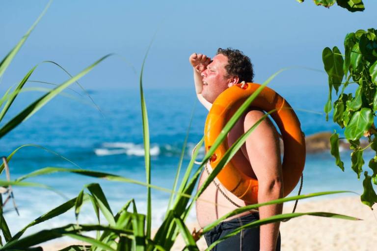 man with sunburn checking the surf with a floatie on his shoulder