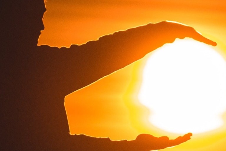 person framing the sun with hands